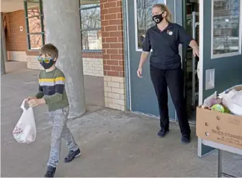  ?? Matt Freed/Post-Gazette photos ?? Finley Dubin, 7, picks up his meal from Trista Boyes at Dormont Elementary School.