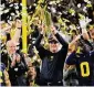  ?? ?? Michigan head coach Jim Harbaugh celebrates with the trophy after their win in the national championsh­ip College Football Playoff game against Washington Monday in Houston.