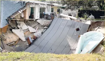  ?? AP ?? The home of Michael and Janni Dupre is destroyed after the backyard behind the home collapsed into a sinkhole, taking their patio and boat, on Thursday, Nov. 14, 2013. in Dunedin, Fla. Dunedin Deputy Fire Chief Trip Barrs said the hole appeared to be...