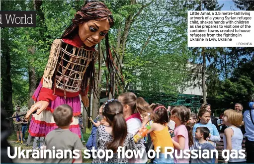  ?? LEON NEAL ?? Little Amal, a 3.5 metre-tall living artwork of a young Syrian refugee child, shakes hands with children as she prepares to visit one of the container towns created to house refugees from the fighting in Ukraine in Lviv, Ukraine