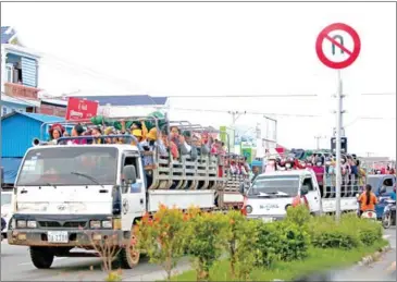  ?? HENG CHIVOAN ?? Garment workers commute in open-bed trucks on National Road 3 in May last year.