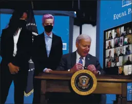  ?? EVAN VUCCI — THE ASSOCIATED PRESS ?? United States Soccer Women’s National Team members Margaret Purce, left, and Megan Rapinoe, center, look on as President Joe Biden signs a proclamati­on recognizin­g Equal Pay Day on Wednesday in Washington.