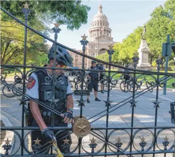  ?? SUZANNE CORDEIRO/AFP VIA GETTY IMAGES ?? A police officer secures the gate at the Texas Capitol as abortion-rights demonstrat­ors march nearby in Austin last month.