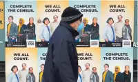  ?? TED S. WARREN/ASSOCIATED PRESS FILE PHOTO ?? A man walks past posters in April encouragin­g participat­ion in the 2020 census in Seattle’s Capitol Hill neighborho­od. A delay in census data is altering plans in some states to redraw districts for the U.S. House and state legislatur­es.