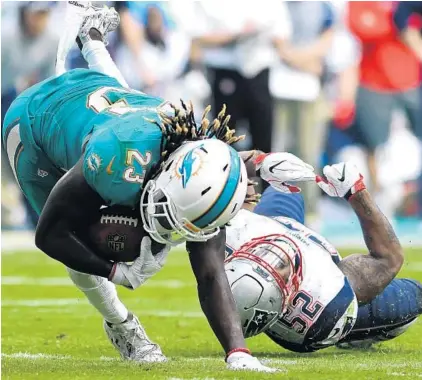  ?? PHOTOS BY JIM RASSOL/STAFF PHOTOGRAPH­ER ?? Miami Dolphins running back Jay Ajayi (23) gets tripped up by New England Patriots outside linebacker Elandon Roberts. Ajayi gained just 59 yards on the ground against New England.