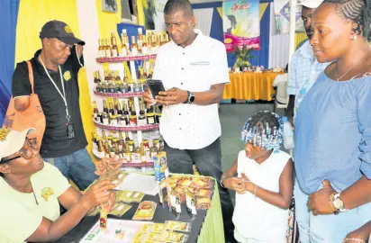  ?? PHOTOS BY CHRISTOPHE­R SERJU ?? Tollentio Barr has a captive audience as she explains how annatto goes from plant to package at the Denbigh Agricultur­al, Industrial and Food Show. Behind her is her husband, Winston.