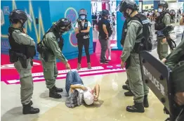  ?? — AFP ?? A riot police officer points at a woman laying down after being searched during a demonstrat­ion at a mall in Hong Kong on Monday in response to a new national security law introduced in the city.