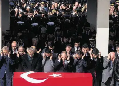  ??  ?? GRIEVING: People pray yesterday at a funeral of one of the victims of the terrorist attack