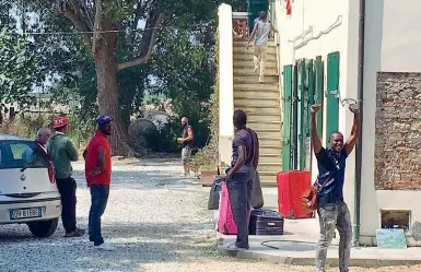  ??  ?? E i residenti invitano la sindaca a cena I migranti lasciano festanti la struttura dopo la notifica della Prefettura di Pisa. Il sindaco di Cascina Susanna Ceccardi (sopra), con un gruppo di residenti, mostra il segno della vittoria: gli abitanti della zona hanno deciso di organizzar­e una cena con lei per il 31 agosto, «per festeggiar­e la chiusura del centro»