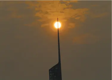  ?? Don Ryan / Associated Press ?? A glowing sun, muted by wildfire smoke, is visible behind the spire of the Convention Center in Portland.