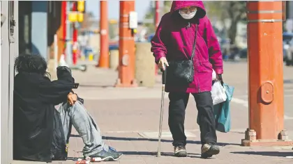  ?? LARRY WONG ?? A woman walks past a man on 97 Street Monday in Chinatown, a city district that needs more supportive housing, mayor Don Iveson says.