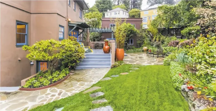  ?? George Draper Photograph­y ?? Above: Lush vegetation provides vibrant colors in the gently sloping backyard of this home on San Luis Road in the North Berkeley hills. Below: The living room features a raised ceiling, wood-framed windows and a brick wood-burning fireplace.