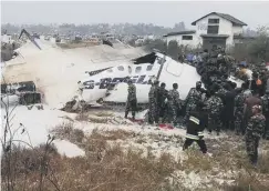  ??  ?? 0 Rescuers surround the plane shortly after it crashed in Nepal