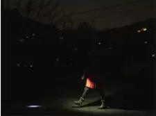  ?? EVGENIY MALOLETKA — THE ASSOCIATED PRESS ?? A woman lights up the road with a flashlight during blackout in Kyiv, Ukraine, on Friday.