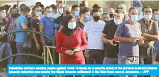  ?? —AFP ?? Palestinia­n workers wearing masks against Covid-19 lineup for a security check at the entrance to Israel’s Mishor Adumim industrial zone nearby the Maale Adumim settlement in the West Bank east of Jerusalem.