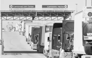  ??  ?? Trucks wait in a long queue for border customs control to cross into the US at the Otay border crossing in Tijuana, Mexico. Facing US President Donald Trump’s protection­ist threats, Mexico is looking to expand trade ties with Europe and Asia, but...