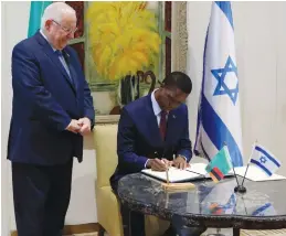  ?? (Reuters) ?? PRESIDENT REUVEN RIVLIN looks on as Zambian President Edgar Chagwa Lungu signs the guest book yesterday during their meeting at his Jerusalem residence.