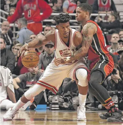  ??  ?? Bulls star Jimmy Butler ( working against the Heat’s Rodney McGruder) scored only three points on 1- for- 13 shooting Friday.