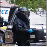  ??  ?? AP/Newsday/CRAIG RUTTLEA New York Police Department bomb unit member holds a case Friday containing a suspicious package discovered at a post office in midtown Manhattan.