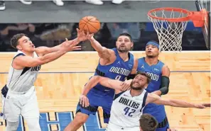  ?? JOHN RAOUX/AP ?? Mavericks center Dwight Powell, left, and forward Maxi Kleber (42) go after a rebound against Magic center Nikola Vucevic, center, and forward Chuma Okeke, back right, during the second half on Monday.