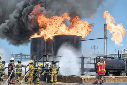  ?? Brett Coomer / Staff photograph­er ?? Emergency responders from Latin America fight a simulated fire in a storage tank during their training at Disaster City, just west of Texas A&M University in College Station. The institute brings first responders from around the world.