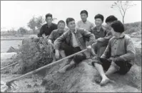  ?? LIU WEIFENG / CHINA DAILY ?? Left: Wu Renbao (center), former Party chief of Huaxi village, chats with residents in the 1970s. PROVIDED TO CHINA DAILY Right: A sculpture at the entrance to Yonglian village, Jiangsu, stands as a symbol of Yonglian’s unity, and commemorat­es former village Party chief Wu Dongcai.