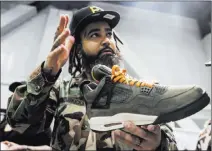  ??  ?? Jaysee Lopez, owner of the Urban Necessitie­s shop in Boulevard Mall in Las Vegas, holds the Undefeated Air Jordans he says are likely to sell in 20 minutes for $16,000.