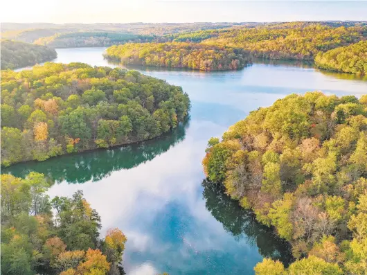  ?? JERRY JACKSON/BALTIMORE SUN ?? Clouds are reflected in the surface of Prettyboy Reservoir as the rising sun accentuate­s the leaves which are just starting to show some fall coloring.