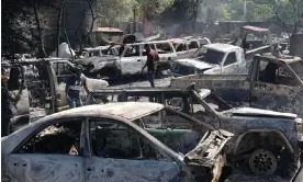  ?? Photograph: Odelyn Joseph/AP ?? People look for salvageabl­e pieces from burned cars at a shop that was set on fire by armed gangs in Port-au-Prince on 25 March.