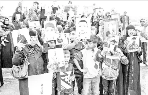  ??  ?? Iraqis hold up portraits of missing relatives who were held captive by IS group fighters, during a demonstrat­ion in the eastern part of the northern city of Mosul.