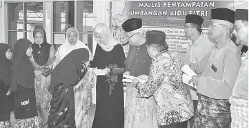  ??  ?? Talib (fourth left) and Dr Zaleha, on his right, give away ‘duit Raya’ to the orphans from Bintulu Peryatim Complex.