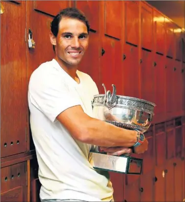  ??  ?? SATISFACCI­ÓN ÍNTIMA. Rafa Nadal abraza la Copa de los Mosquetero­s en el vestuario de la Chatrier.