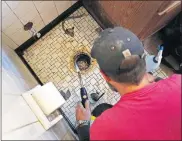  ??  ?? Trevor Brown, with Herman's Plumbing, repairs a toilet during work in a senior's house on NE 27 during a RestoreOKC workday.