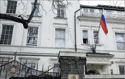  ?? Alastair Grant ?? A man works to untangle the national flag flown Wednesday from the Russian Embassy in London. Britain announced it will expel 23 Russian diplomats and severe high-level contacts after the poisoning of a former spy.