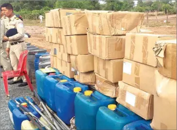  ?? NATIONAL POLICE ?? Police stand by boxes of seized products before they are destroyed in Kampong Speu province.