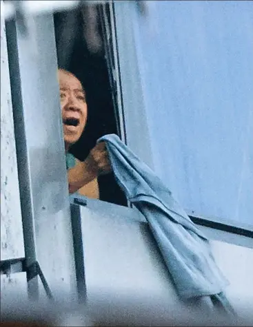  ??  ?? Cry for help: The man waves a jersey out of a window of his 11th-floor flat