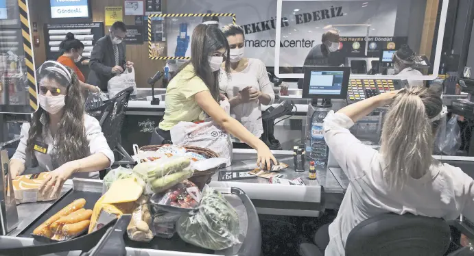  ??  ?? People wearing face masks shop for food at a grocery store hours before a four-day curfew, Ankara, Turkey, May 22, 2020.