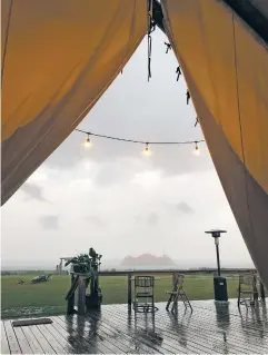  ?? PHOTO BY LAURA MARTIN ?? The Staten Island Ferry looms out of a rain squall, with the drenched outdoor dining area of the campsite in the foreground.