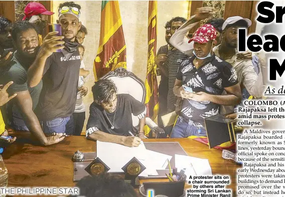  ?? AP ?? A protester sits on a chair surrounded by others after storming Sri Lankan Prime Minister Ranil Wickremesi­nghe’s office, demanding he resign after President Gotabaya Rajapaksa fled the country amid the economic crisis in Colombo, Sri Lanka on Wednesday.