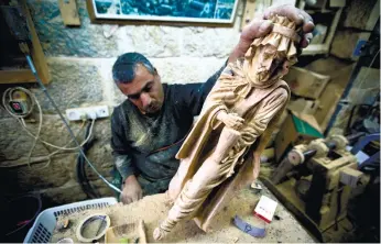  ?? (AP FOTO) ?? CHRISTMAS SOUVENIRS. Palestinia­n woodcarver Muhammad Yusuf, works on olive wood figures in the West Bank city of Bethlehem.While craft workshop owners grumble about foreign imports, not everyone believes the imports have seriously threatened local...