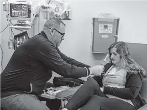  ?? JAHI CHIKWENDIU/THE WASHINGTON POST ?? Robbie Wilson removes Emily Domhoff’s chemothera­py infusion pump. Dumhoff was in her late 20s when she was diagnosed with colon cancer. She received chemo drugs through a port in her chest every two weeks this spring and summer.