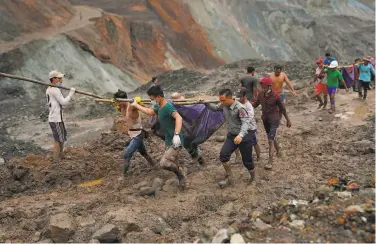  ?? Zaw Moe Htet / AFP via Getty Images ?? Rescuers recover bodies near the landslide area in the jade mining site in Kachin state, Myanmar.