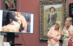  ??  ?? Visitors look at a monitor showing the damaged painting Ivan The Terrible And His Son Ivan.