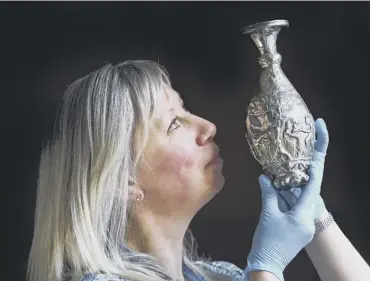  ?? PICTURE; NEIL HANNA ?? 0 A curator holds up one of the pieces of Traprain Law silver