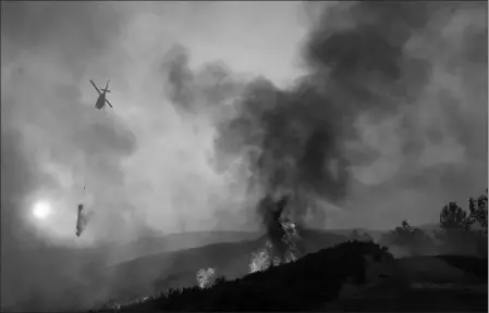  ?? ASSOCIATED PRESS ?? A HELICOPTER DROPS WATER ON A BURNING HILLSIDE during the Ranch Fire in Clearlake Oaks, Calif., on Sunday.