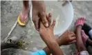  ?? Photograph: Daniel Becerril/Reuters ?? A migrant washes the hands of a child at an encampment in Matamoros, Mexico, as more than 2,000 migrants seek asylum in the US.