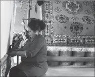  ??  ?? A woman weaves a carpet by hand at a local workshop in the Xinjiang Uygur autonomous region in May.