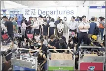  ??  ?? In this file photo, airport security personnel stand guard as travelers walk past protesters holding a sit-in rally at the departure gate of the Hong Kong Internatio­nal Airport in Hong Kong. Visitor numbers to Hong Kong fell by nearly 40% in the second half of last year amid clashes between police and
anti-government protesters. (AP)