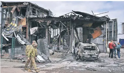  ?? FOTO: ANDRIY ANDRIYENKO/AP ?? Zwei ukrainisch­e Soldaten laufen an einem durch einen russischen Angriff zerstörten Haus in Dnipro vorbei.