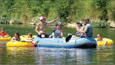  ?? Photo by Randy Moll ?? The Springmann and Greening families, of Bentonvill­e and Orlando, Fla., respective­ly, point to sights along the shoreline as they float down the Elk River near Noel, Mo., on July 20.